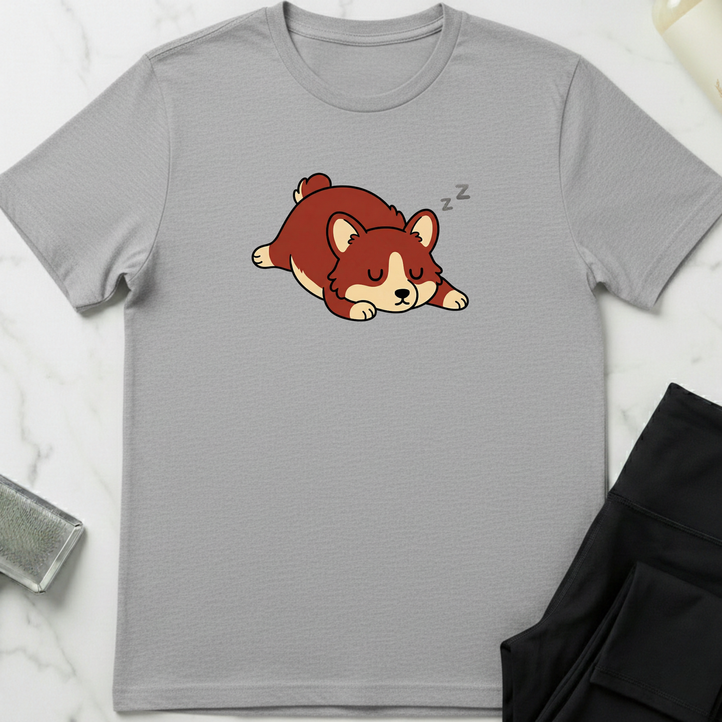 Gray t-shirt with a cartoon dog design on a marble surface. Minimalist dog apparel by pemuyo.