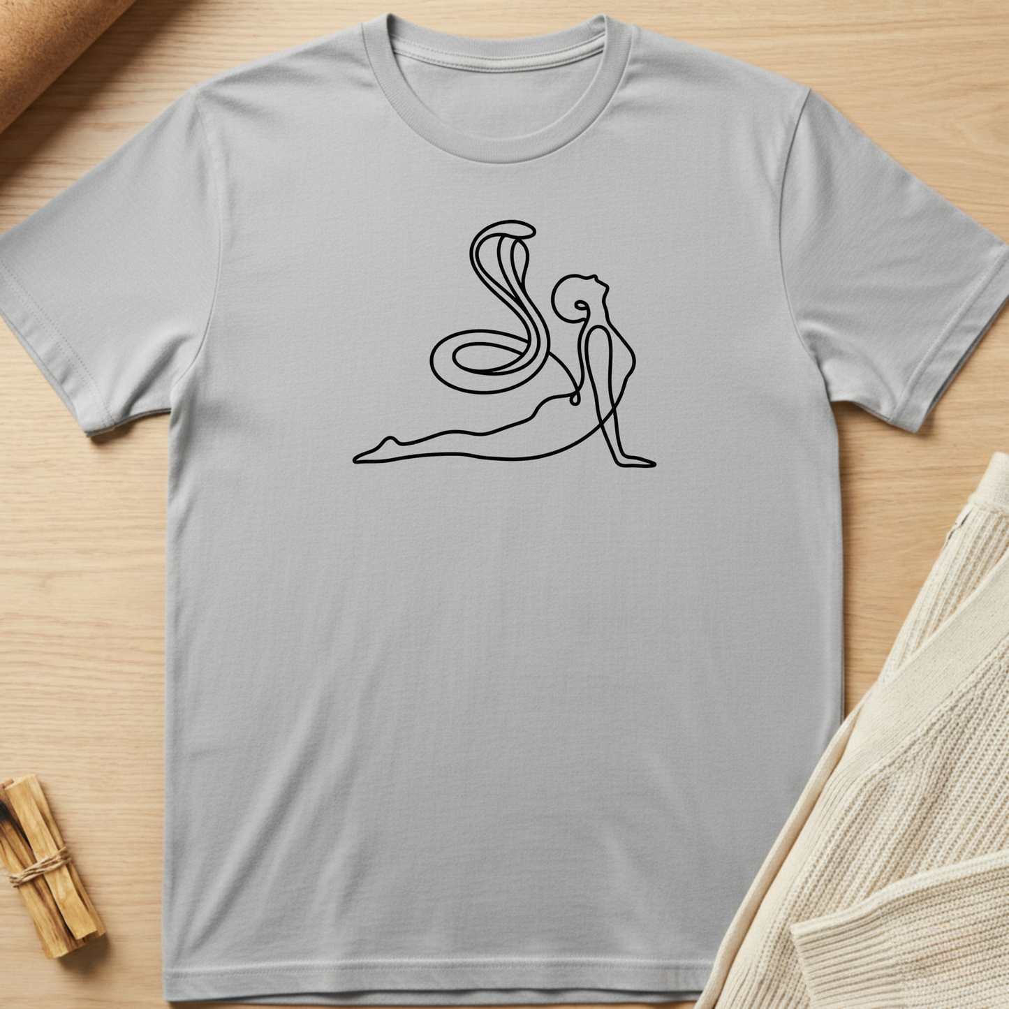 Gray t-shirt with a black line art design of a person in a yoga pose on a wooden surface. Minimalist yoga apparel by pemuyo.