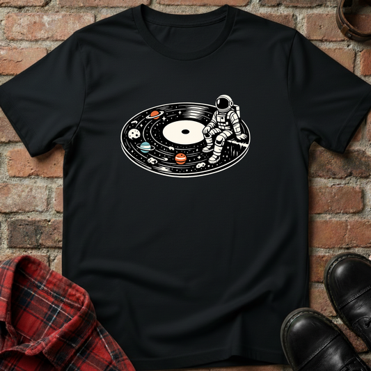 Black t-shirt with an astronaut and vinyl record design on a brick wall background. Minimalist music apparel by pemuyo.