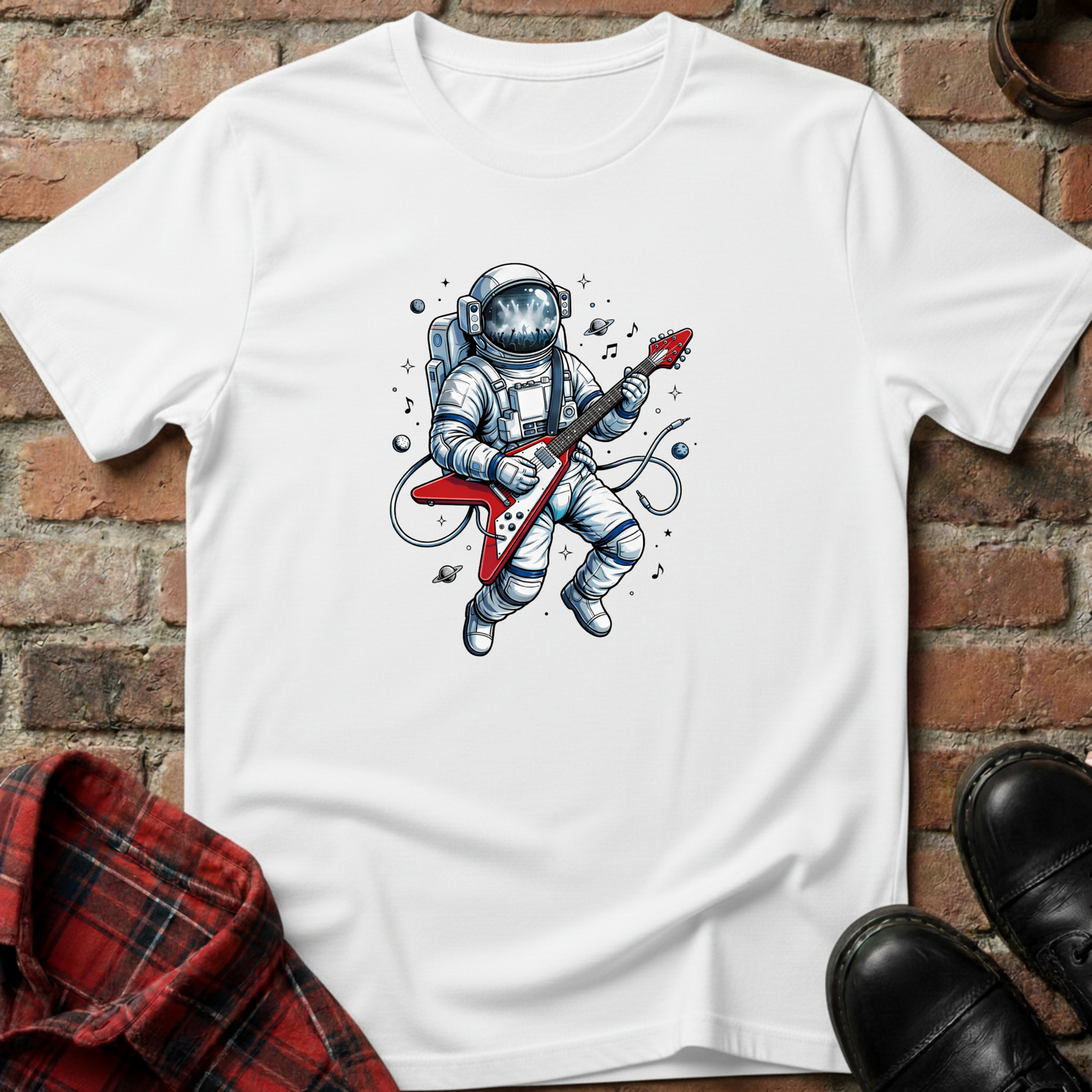 White t-shirt with an astronaut playing a guitar graphic on a brick surface. Minimalist music apparel by pemuyo.