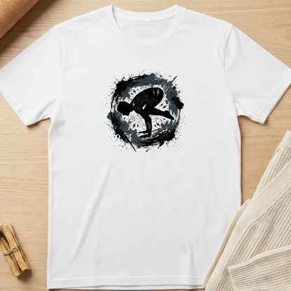 A white short-sleeve crewneck t-shirt laid flat on a light wood surface, featuring a black circular ink-splatter graphic with a stylized human silhouette in the center. Styled flat-lay props include a beige knit fabric at the right and a small wooden bundle at the bottom left. Minimalist yoga apparel by pemuyo.
