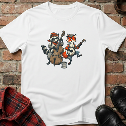 White t-shirt with cartoon raccoon and fox playing instruments on a brick wall background. Minimalist music apparel by pemuyo.