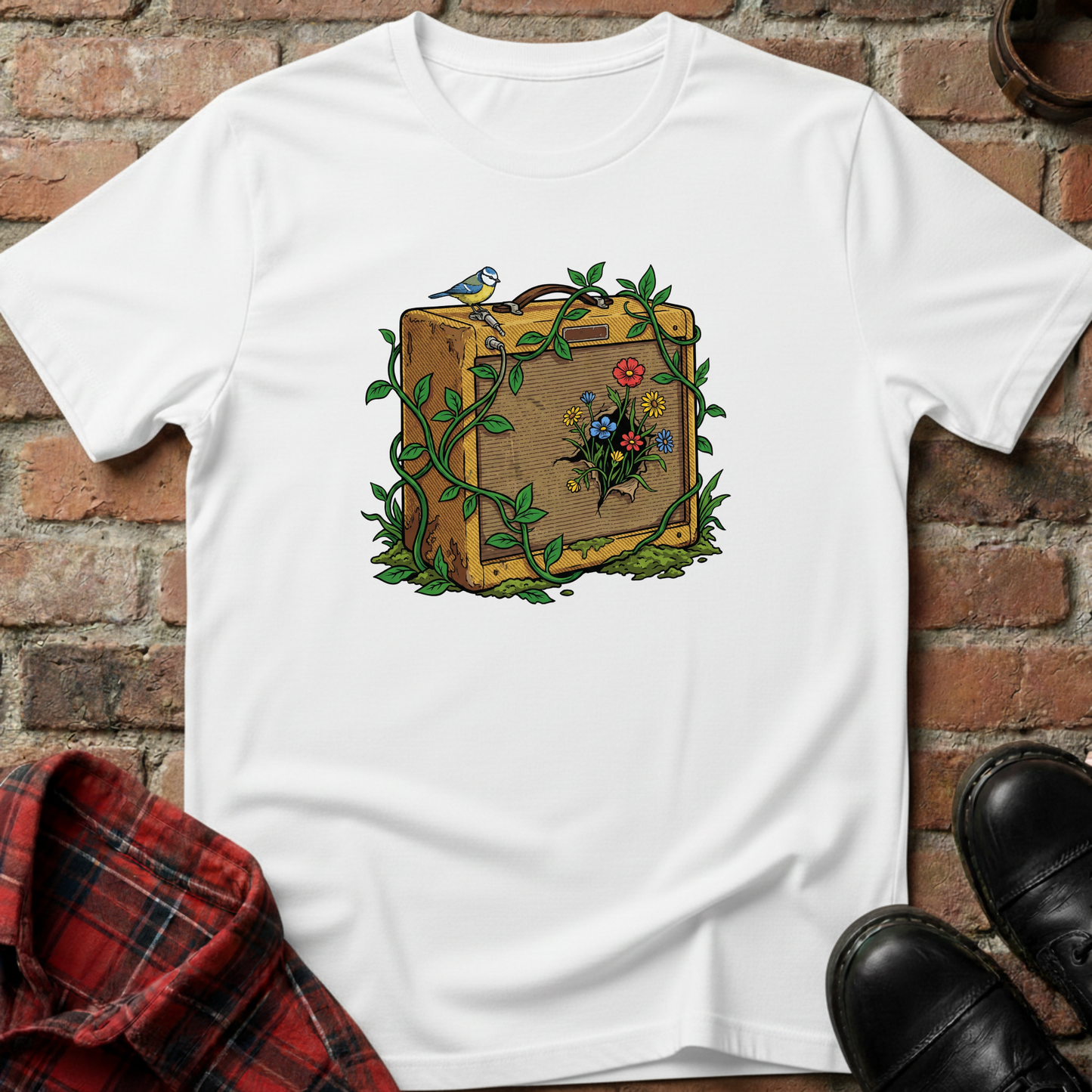 White t-shirt with a suitcase and floral design on a brick surface. Minimalist music apparel by pemuyo.