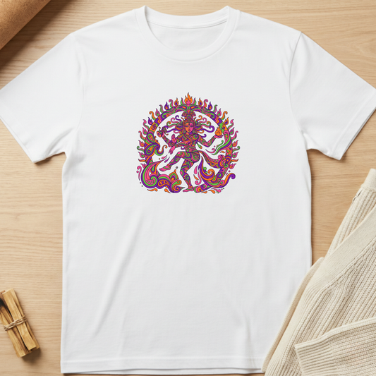 A white short-sleeve crewneck t-shirt laid flat on a light wood surface, featuring a colorful, highly detailed circular graphic of a dancing deity on the chest. Styled flat-lay props include a small bundle of dried herbs in the bottom-left corner and a beige knit fabric in the bottom-right. Minimalist yoga apparel by pemuyo.