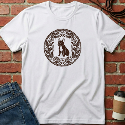 White t-shirt with a brown graphic of a dog and wreath on a brick wall background. Minimalist dog apparel by pemuyo.