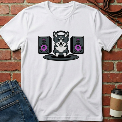 White t-shirt with a dog wearing headphones and speakers design, placed against a brick wall. Minimalist dog apparel by pemuyo.