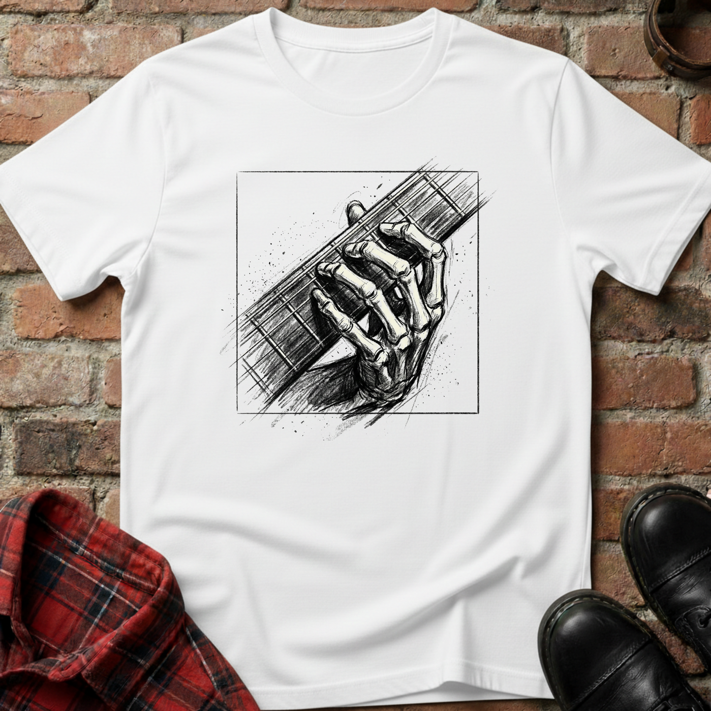 White t-shirt with black and white graphic design of a hand holding a guitar, placed on a brick surface. Minimalist music apparel by pemuyo.
