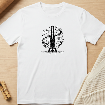 A white short-sleeve crewneck t-shirt laid flat on a light wood background, featuring a black graphic of a champagne bottle with swirling liquid details on the chest. Minimalist yoga apparel by pemuyo.