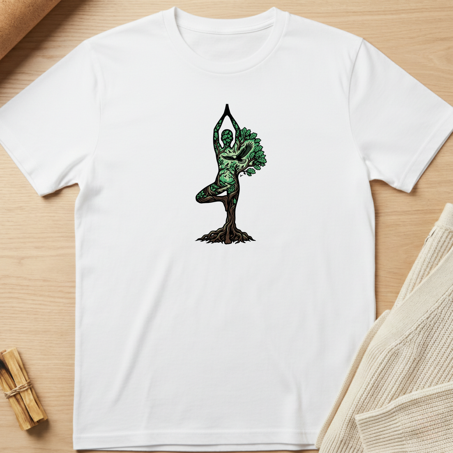 White t-shirt with a tree-dwelling figure design on a wooden surface. Minimalist yoga apparel by pemuyo.