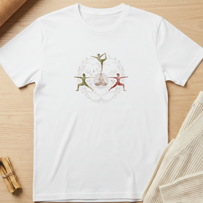 A white short-sleeve crewneck t-shirt laid flat on a light wood surface, featuring a central graphic of three stylized dancers in green, red, and gold within a circular frame. Styled flat-lay props include a beige knit sweater on the right and a small bundle of wooden sticks on the bottom left. Minimalist yoga apparel by pemuyo.