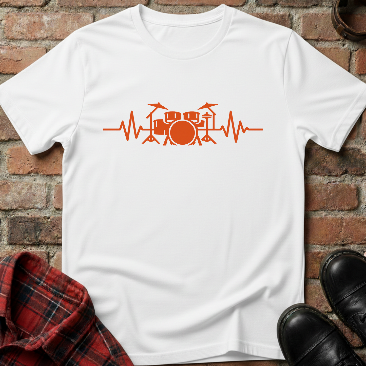 White t-shirt with orange drum design on a brick wall background. Minimalist music apparel by pemuyo.