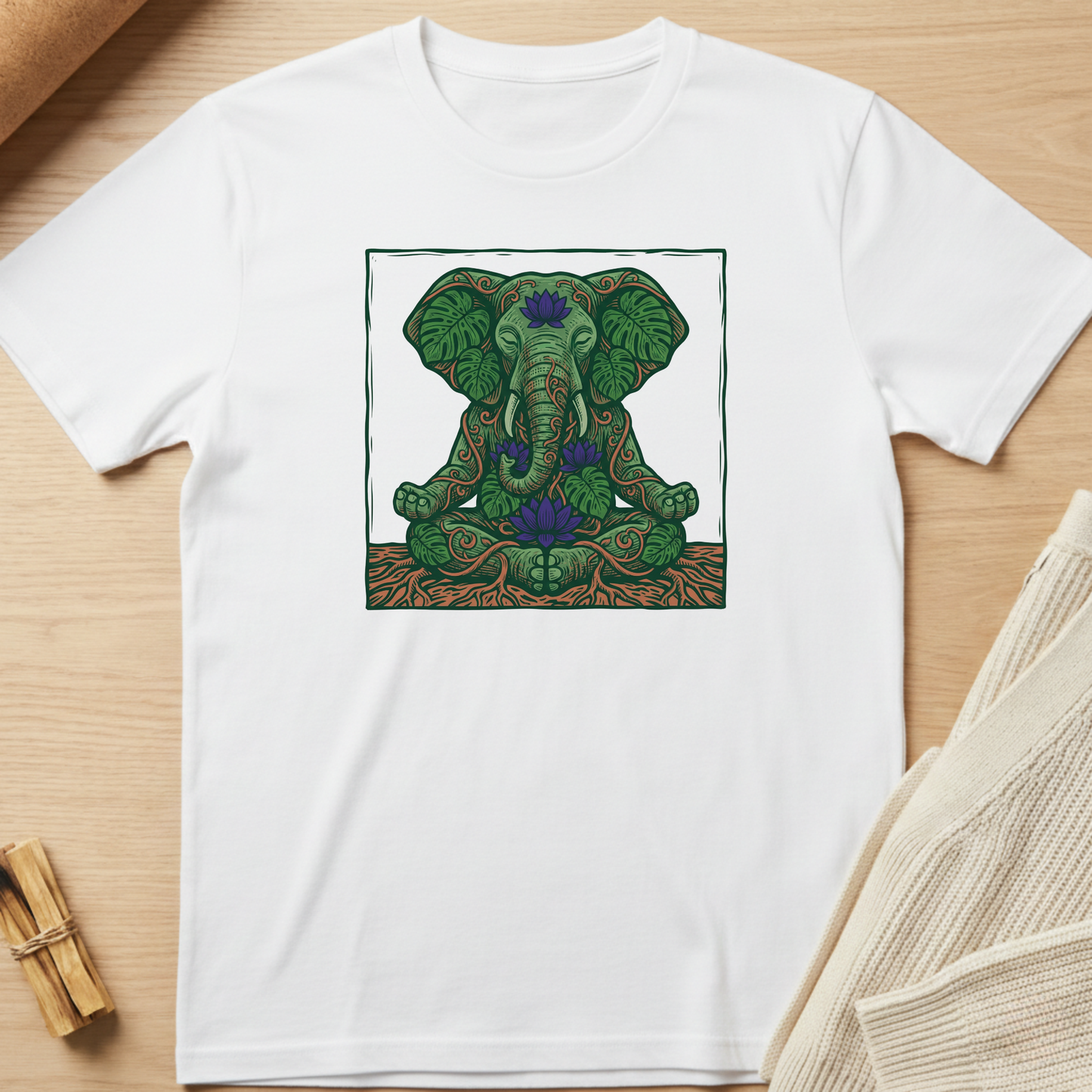 White t-shirt with a green elephant design on a wooden surface. Minimalist yoga apparel by pemuyo.