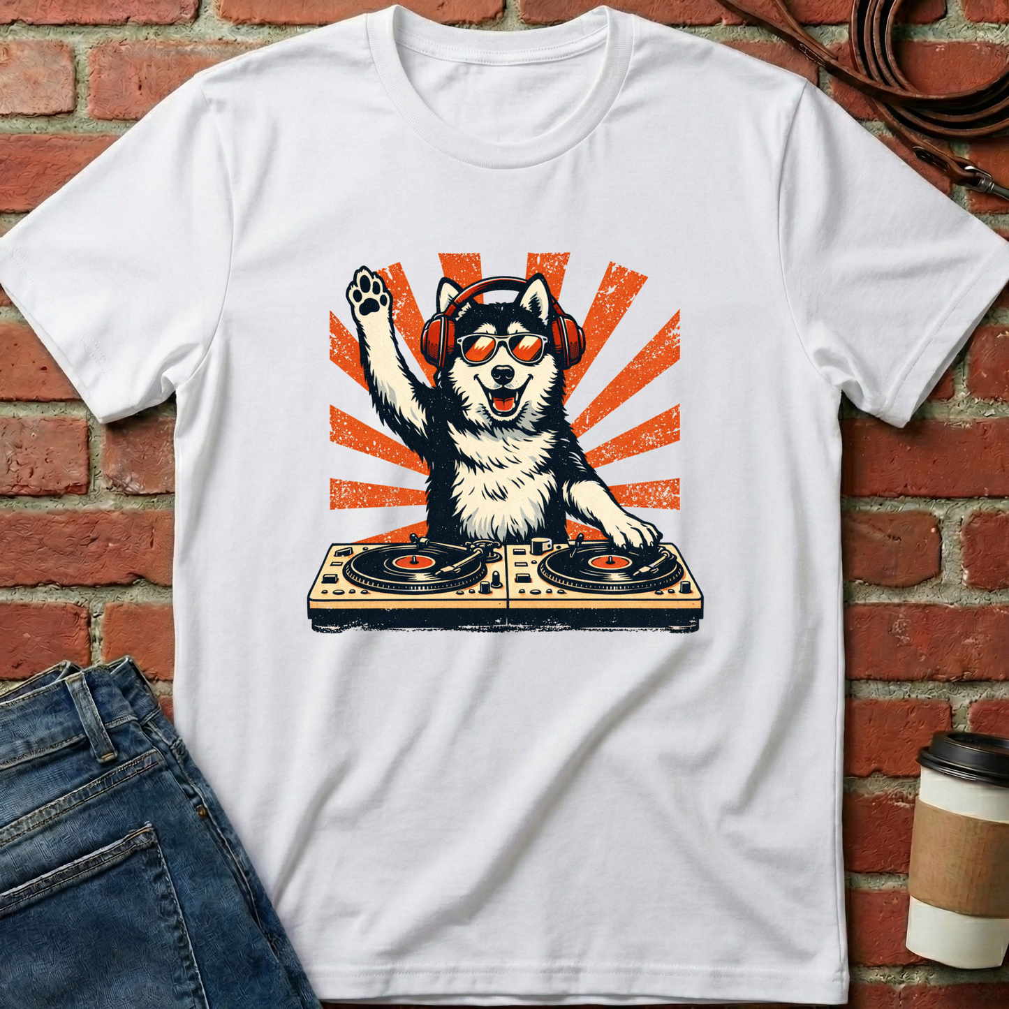 White t-shirt with a dog DJ graphic on a brick wall background. Minimalist dog apparel by pemuyo.