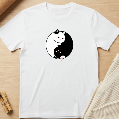 White t-shirt with a yin yang design featuring cartoon cats on a wooden surface. Minimalist yoga apparel by pemuyo.
