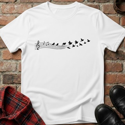 White t-shirt with musical note and bird design on a brick surface. Minimalist music apparel by pemuyo.