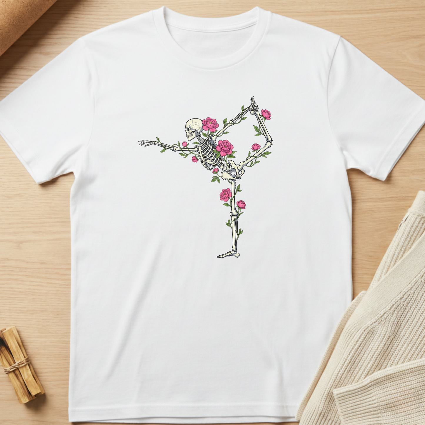 White t-shirt with a skeleton and floral design on a wooden surface. Minimalist yoga apparel by pemuyo.