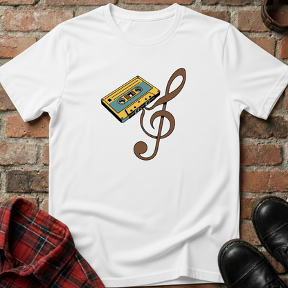White t-shirt with a cassette tape and music note design on a brick surface. Minimalist music apparel by pemuyo.