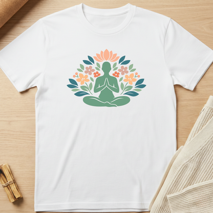 White t-shirt with a green silhouette of a person in meditation surrounded by flowers on a wooden surface. Minimalist yoga apparel by pemuyo.